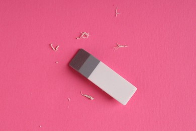 One eraser and scraps on pink background, top view