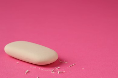 Photo of One eraser and scraps on pink background, closeup. Space for text