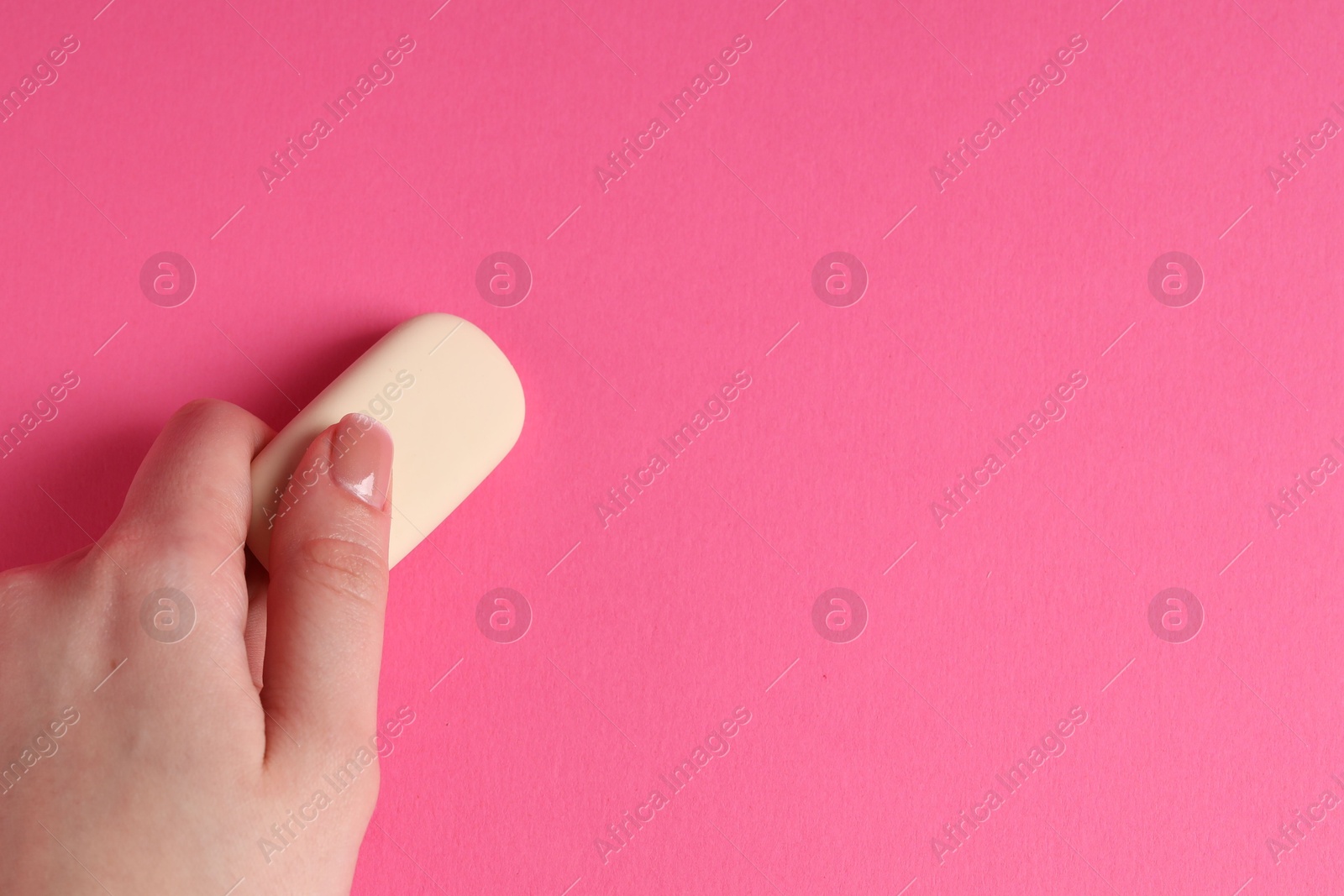 Photo of Woman using eraser on pink background, closeup. Space for text