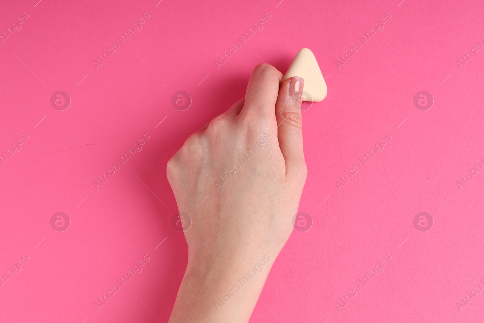 Photo of Woman using eraser on pink background, closeup