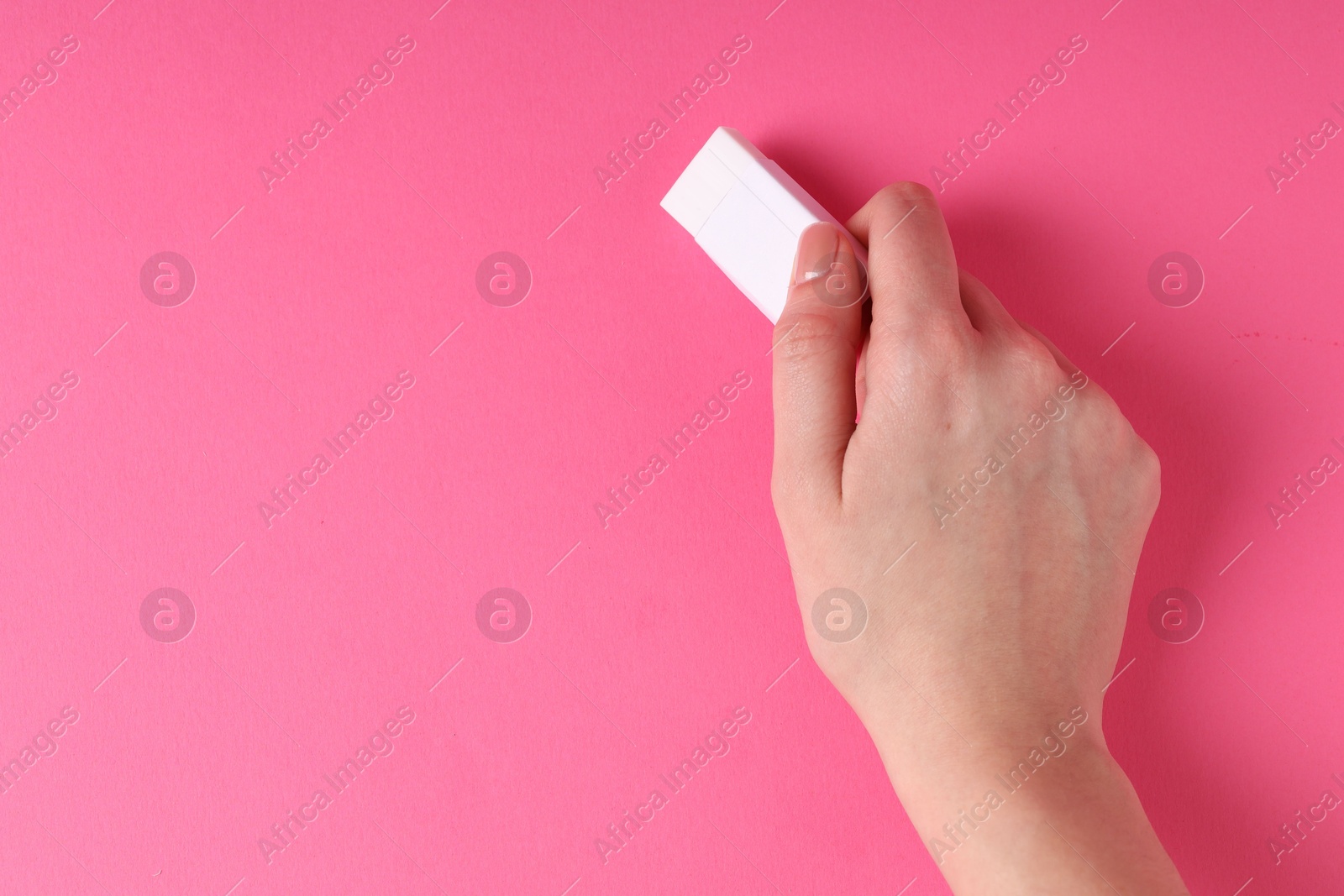 Photo of Woman using eraser on pink background, closeup. Space for text