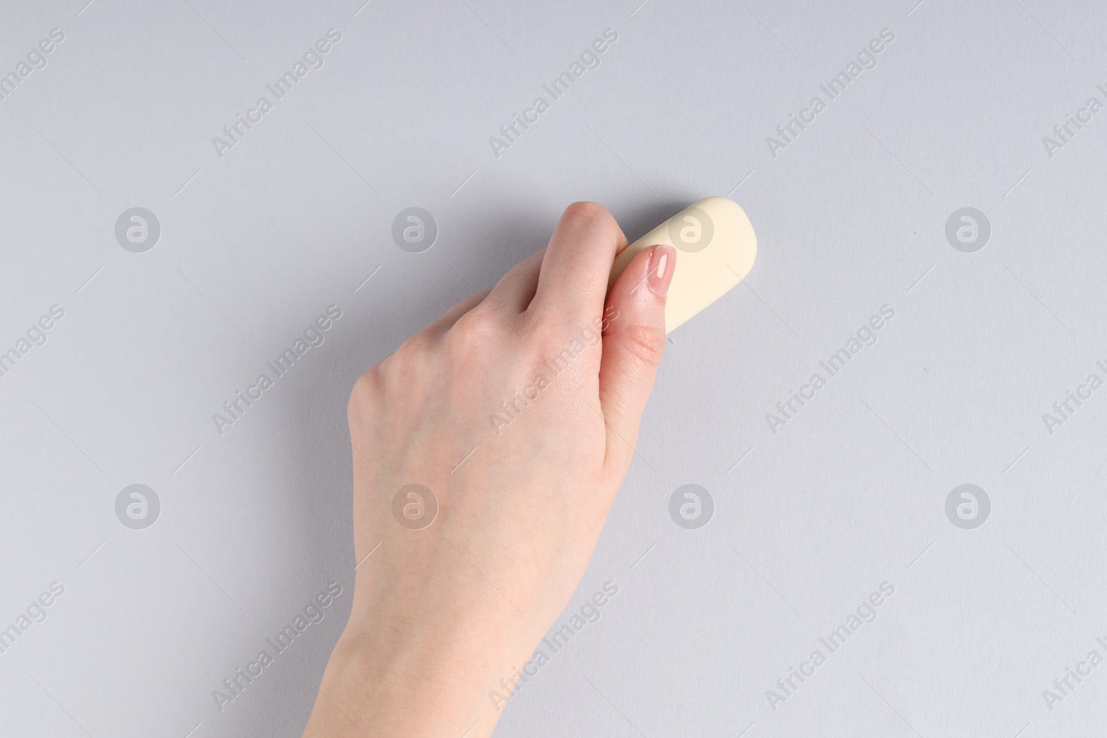 Photo of Woman using eraser on grey background, closeup