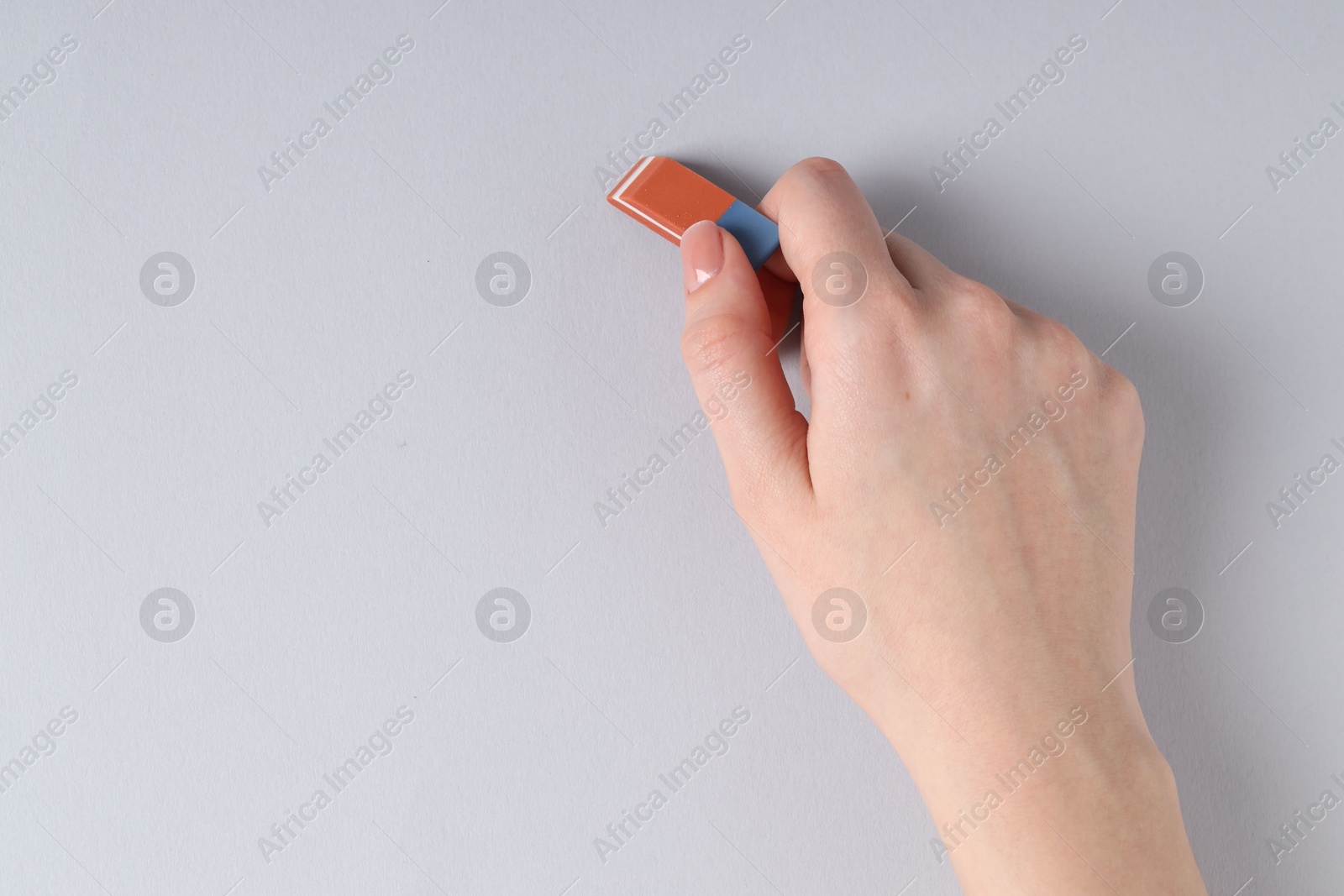 Photo of Woman using eraser on grey background, closeup. Space for text