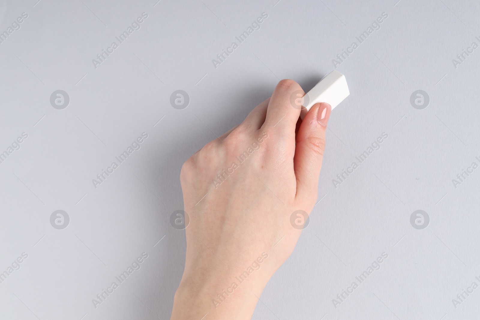 Photo of Woman using eraser on grey background, closeup