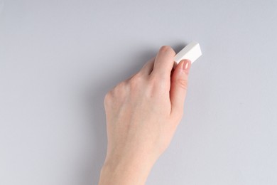 Photo of Woman using eraser on grey background, closeup