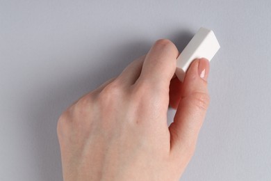 Photo of Woman using eraser on grey background, closeup