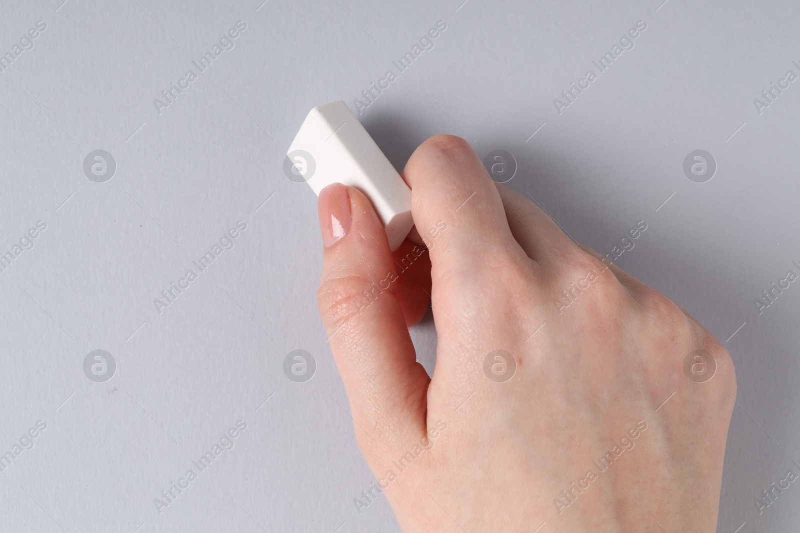 Photo of Woman using eraser on grey background, closeup