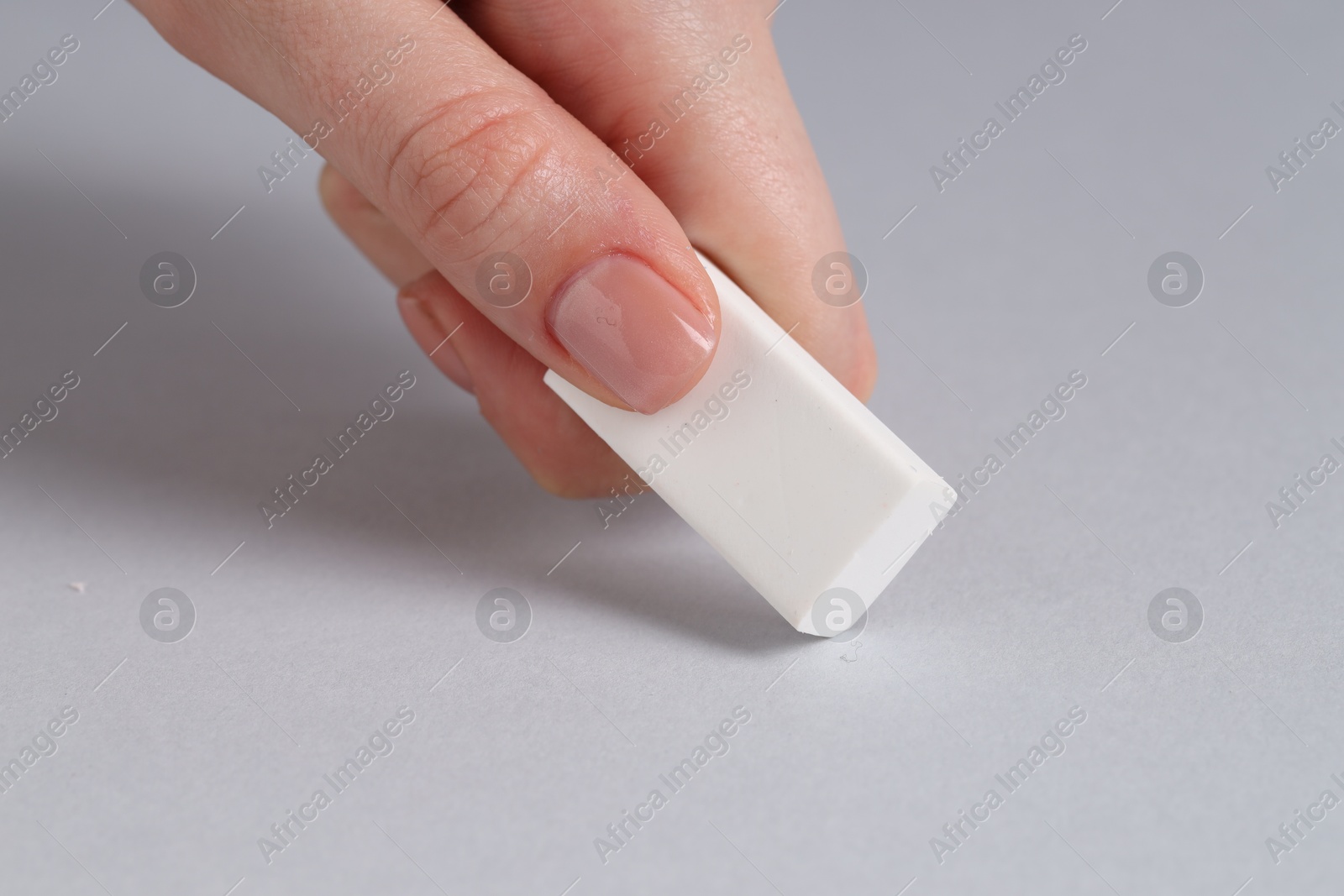 Photo of Woman using eraser on grey background, closeup