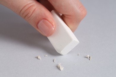 Photo of Woman using eraser on grey background, closeup