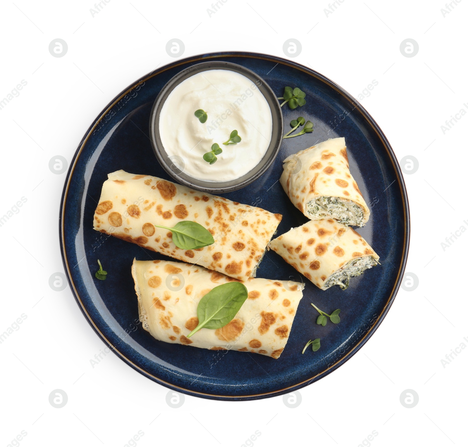 Photo of Delicious crepes with cottage cheese, spinach and sour cream isolated on white, top view