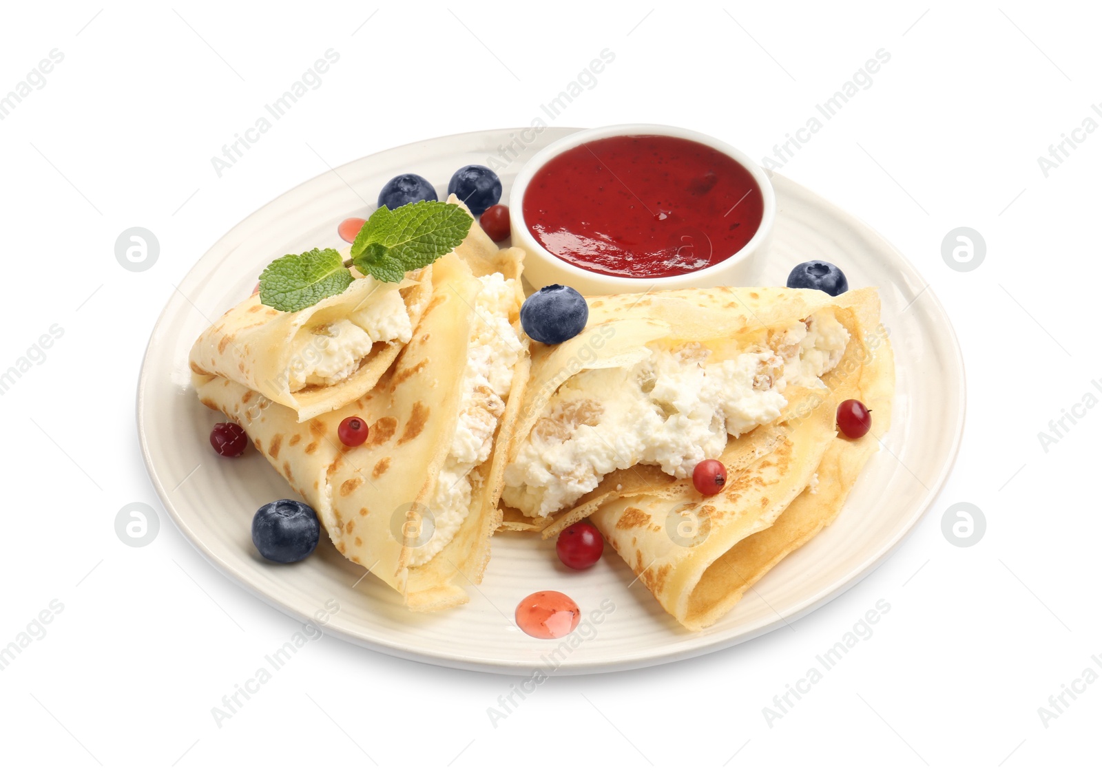 Photo of Delicious crepes with cottage cheese, jam, redcurrants and blueberries isolated on white