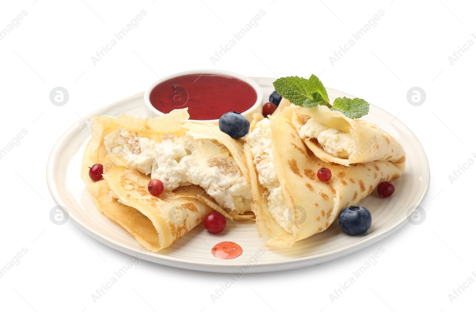 Photo of Delicious crepes with cottage cheese, jam, redcurrants and blueberries isolated on white