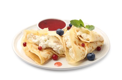 Photo of Delicious crepes with cottage cheese, jam, redcurrants and blueberries isolated on white