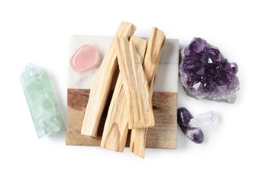 Photo of Palo santo sticks and gemstones isolated on white, top view