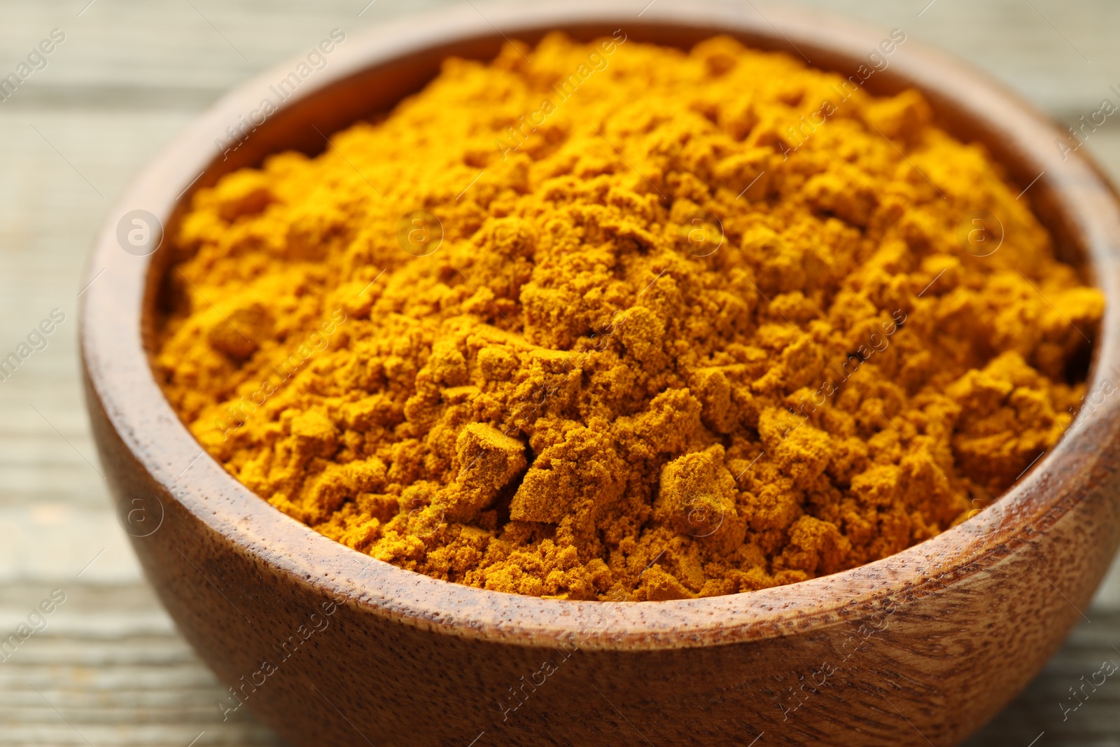 Photo of Turmeric powder in bowl on table, closeup