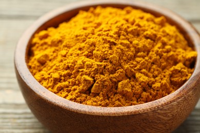 Photo of Turmeric powder in bowl on table, closeup