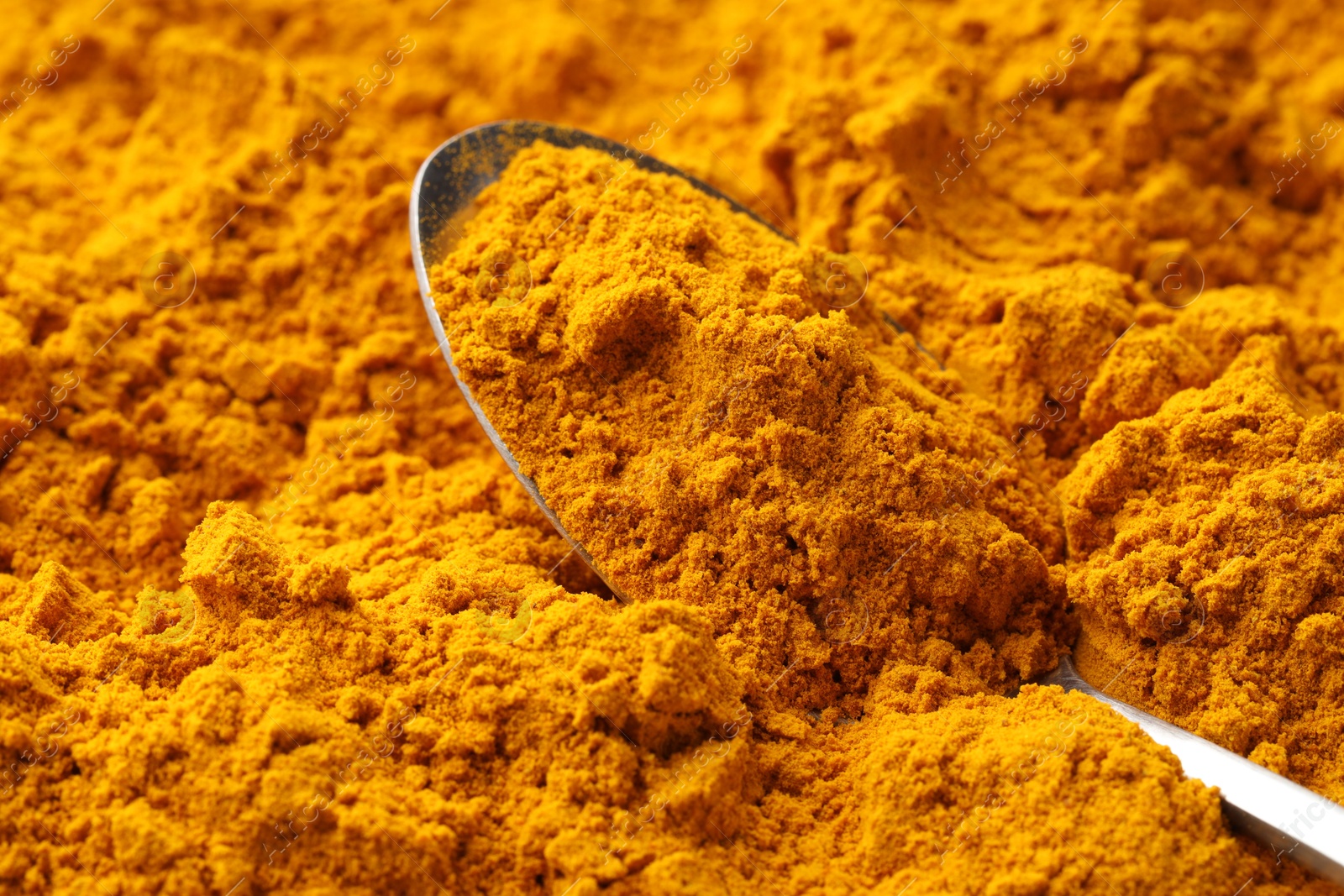 Photo of Turmeric powder in spoon on spice, closeup