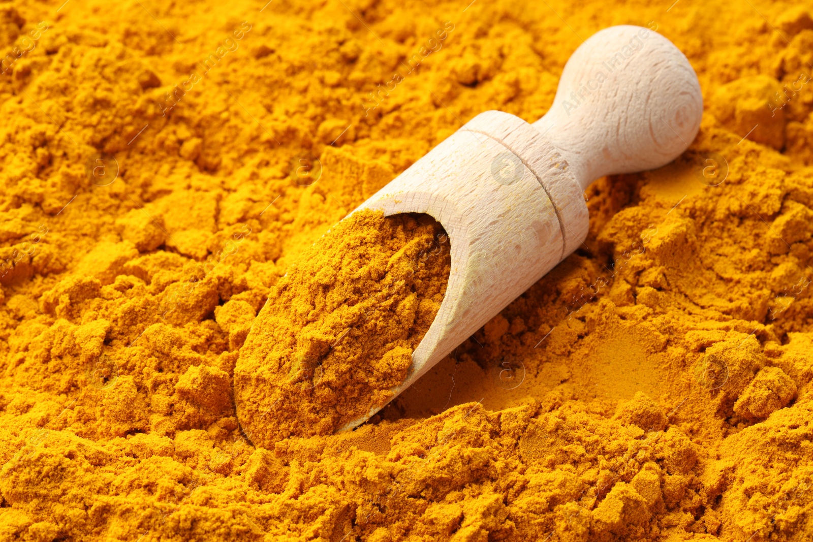 Photo of Turmeric powder in scoop on spice, closeup