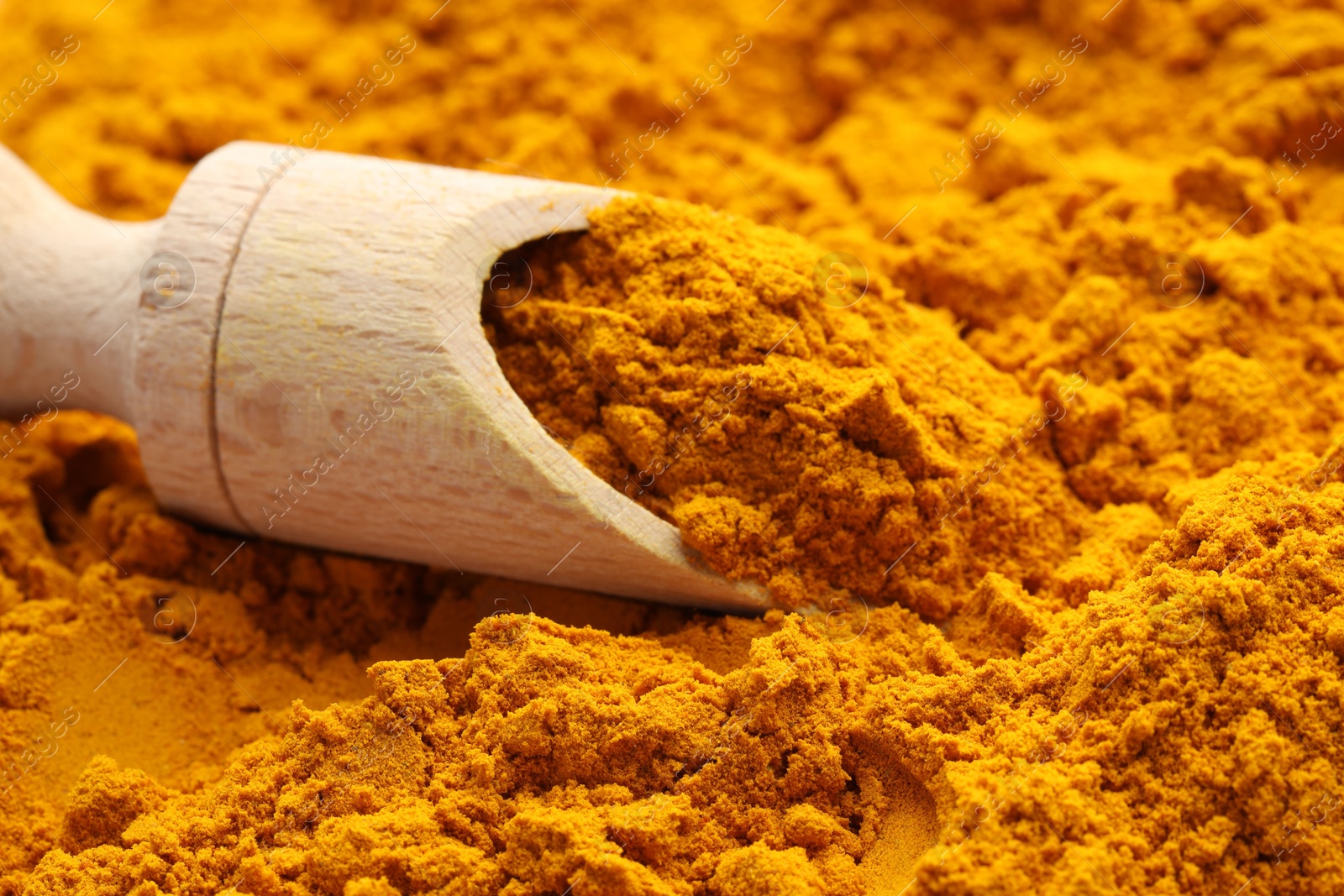 Photo of Turmeric powder in scoop on spice, closeup