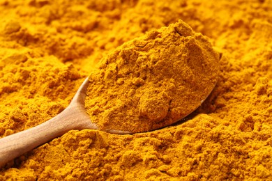 Photo of Turmeric powder in spoon on spice, closeup