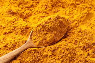 Photo of Turmeric powder in spoon on spice, closeup