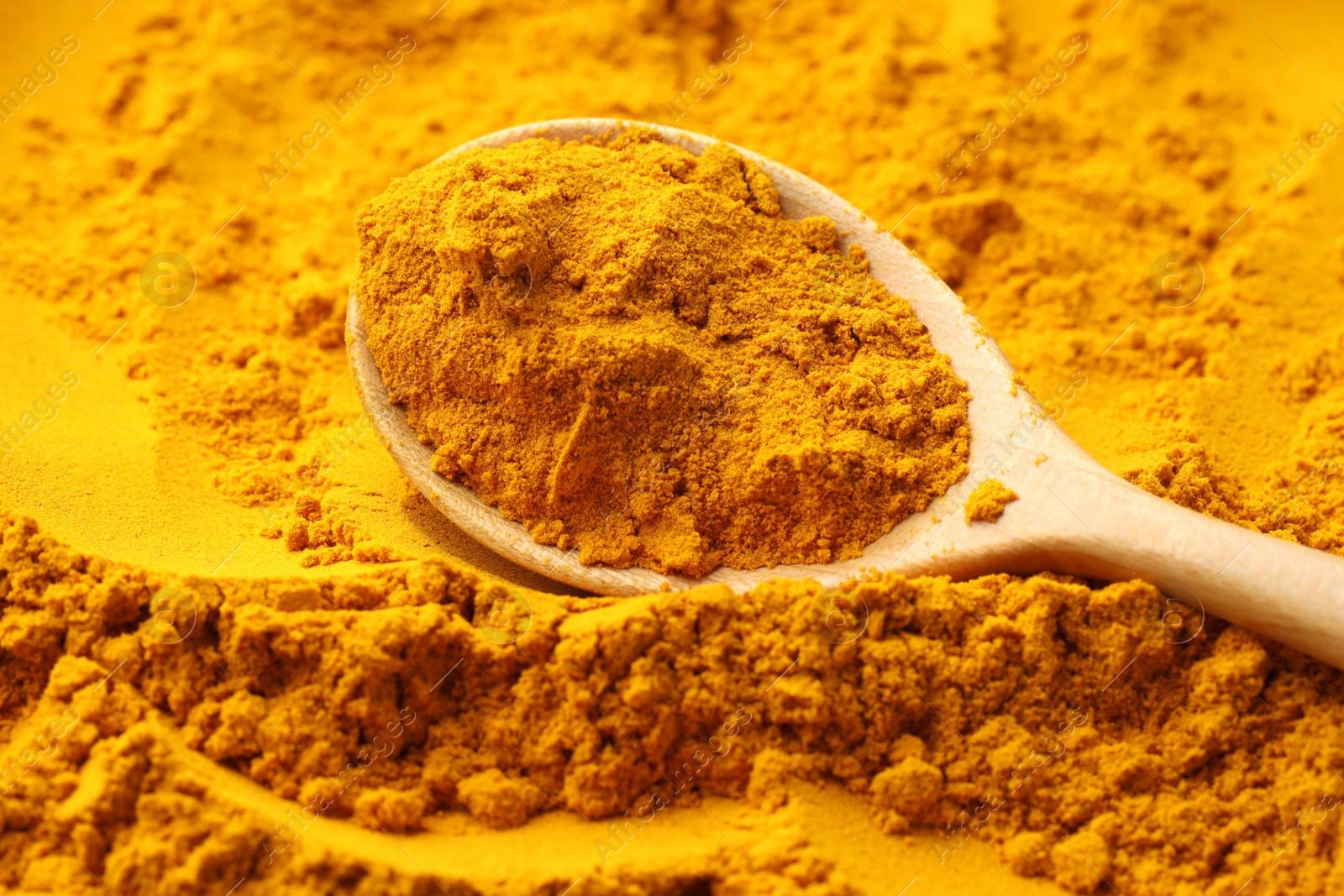 Photo of Turmeric powder in spoon on spice, closeup