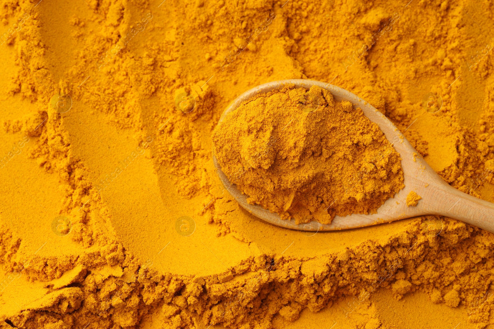 Photo of Turmeric powder in spoon on spice, top view. Space for text