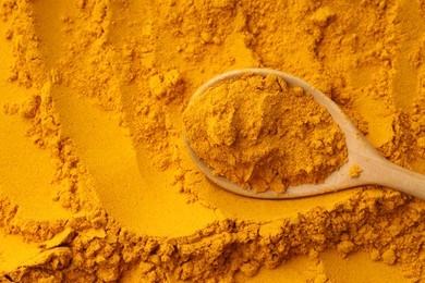 Photo of Turmeric powder in spoon on spice, top view. Space for text