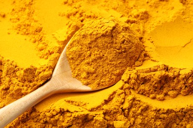 Photo of Turmeric powder in spoon on spice, closeup