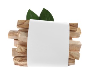 Photo of Palo santo sticks wrapped in paper and green leaves on white background