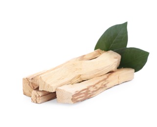 Pile of palo santo sticks and green leaves on white background