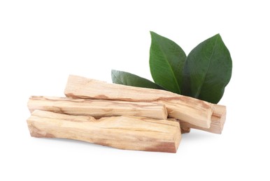 Pile of palo santo sticks and green leaves on white background