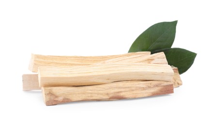 Pile of palo santo sticks and green leaves on white background