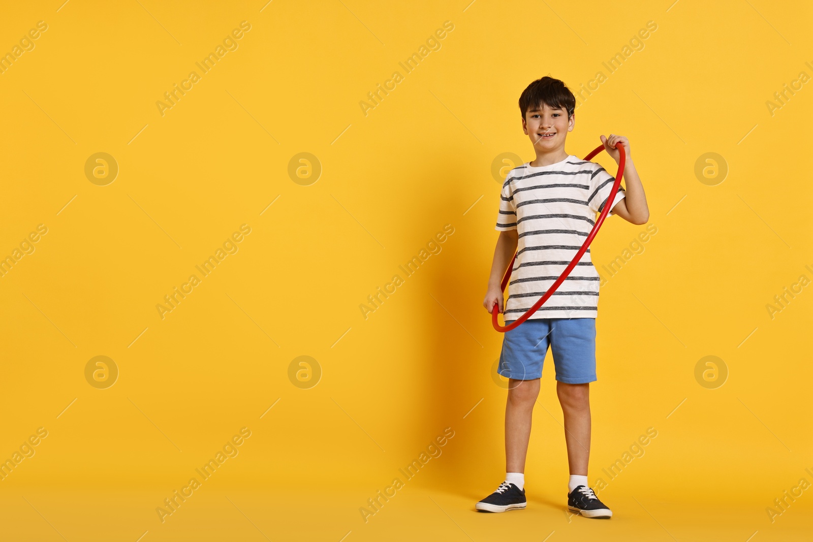 Photo of Smiling boy with hula hoop on yellow background, space for text