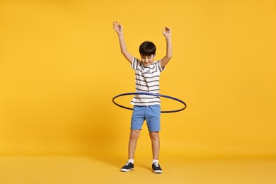 Photo of Boy exercising with hula hoop on yellow background