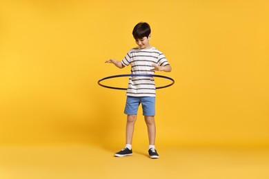 Photo of Boy exercising with hula hoop on yellow background