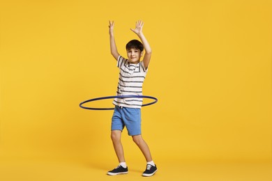 Photo of Boy exercising with hula hoop on yellow background