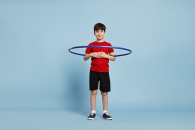 Photo of Boy exercising with hula hoop on light blue background