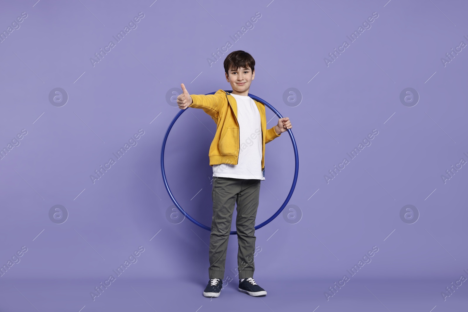 Photo of Boy with hula hoop showing thumbs up on violet background