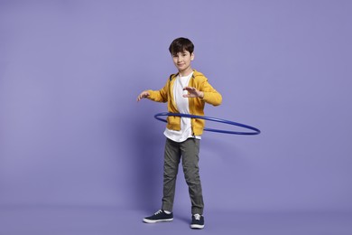 Photo of Boy exercising with hula hoop on violet background