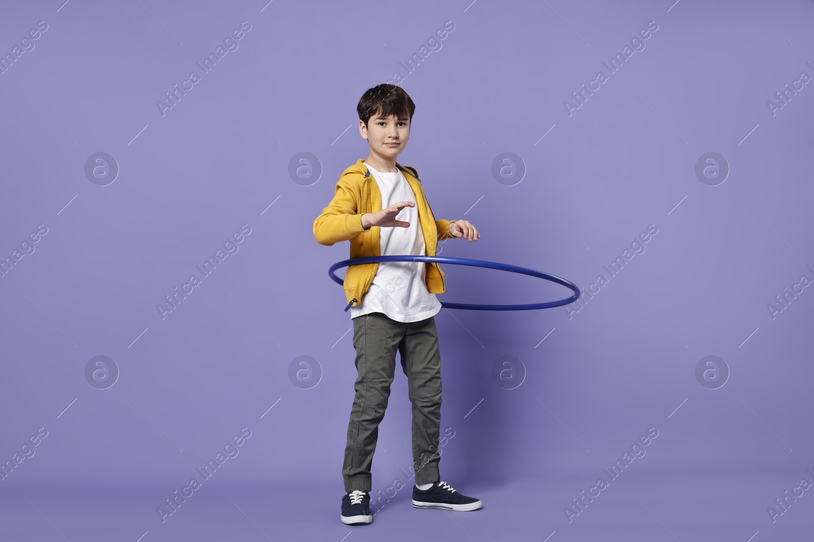 Photo of Boy exercising with hula hoop on violet background