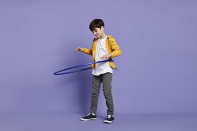 Photo of Boy exercising with hula hoop on violet background