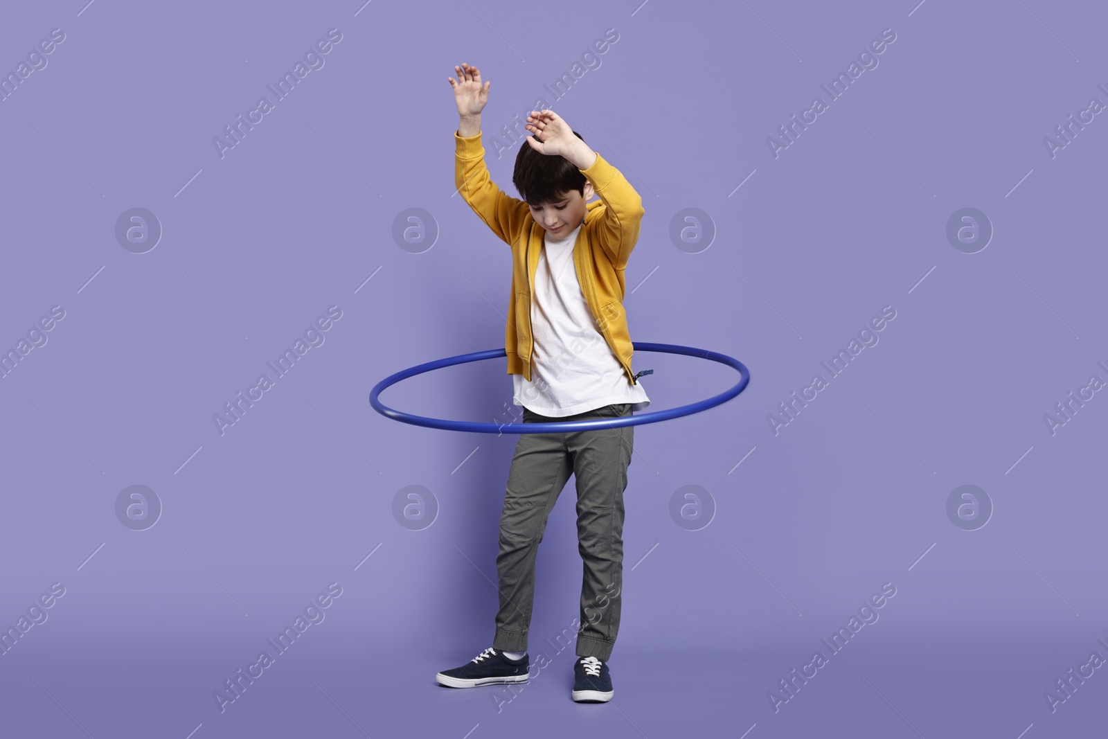 Photo of Boy exercising with hula hoop on violet background