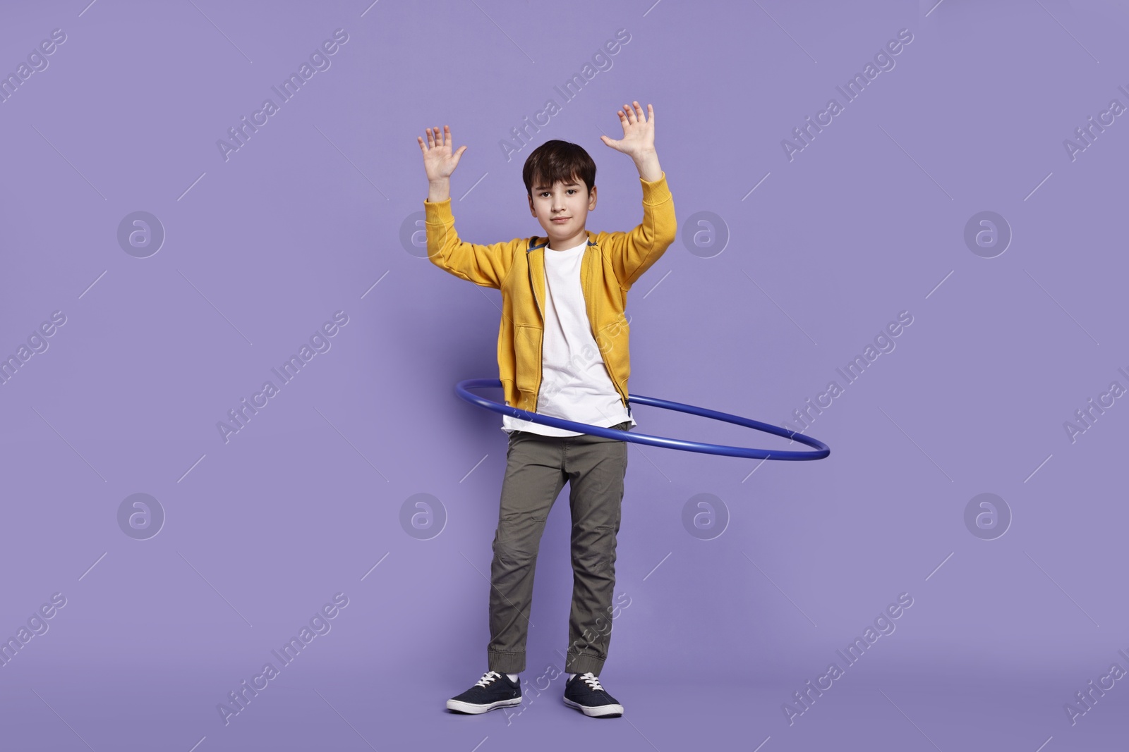 Photo of Boy exercising with hula hoop on violet background