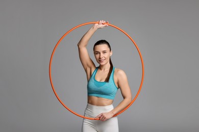 Photo of Smiling woman with hula hoop on grey background