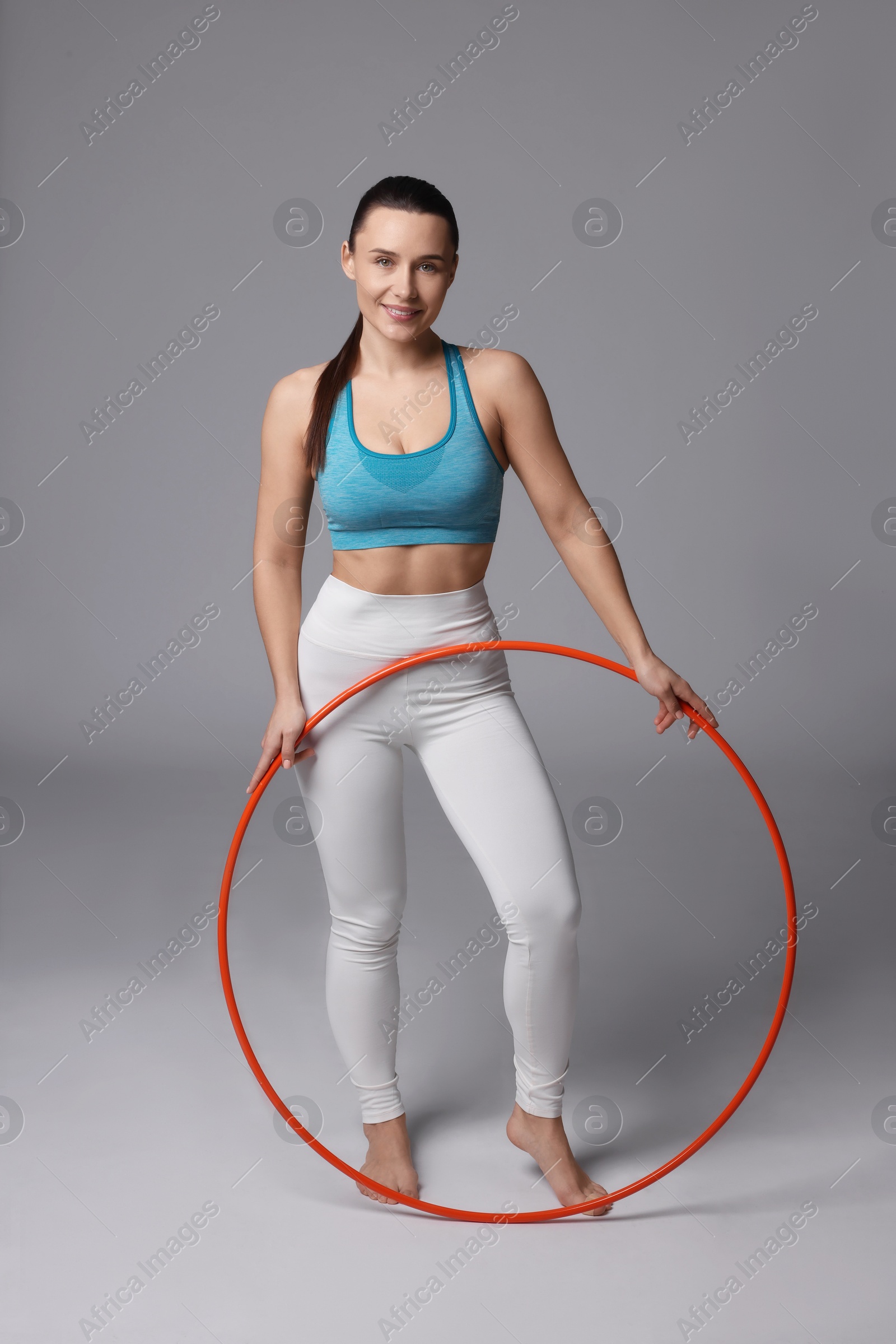 Photo of Smiling woman with hula hoop on grey background