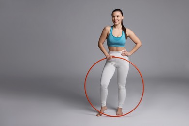 Photo of Smiling woman with hula hoop on grey background. Space for text