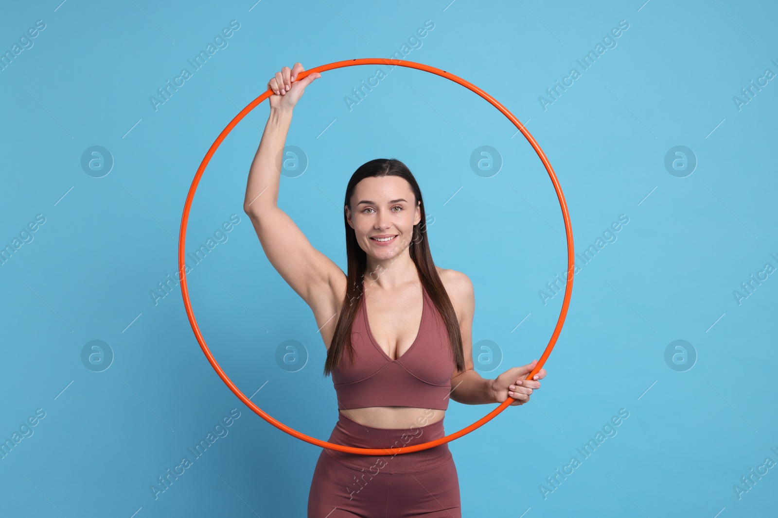 Photo of Smiling woman with hula hoop on light blue background