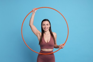 Photo of Smiling woman with hula hoop on light blue background