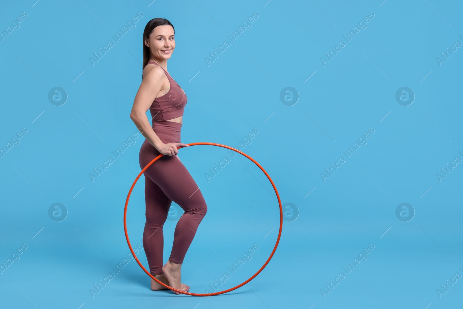 Photo of Smiling woman with hula hoop on light blue background. Space for text